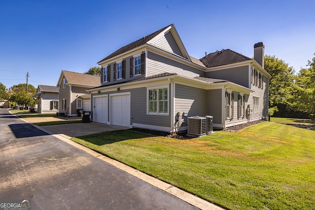 exterior space featuring cooling unit, a front lawn, and a garage