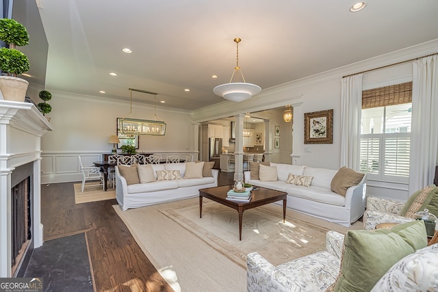 living room with crown molding, a chandelier, and dark hardwood / wood-style flooring