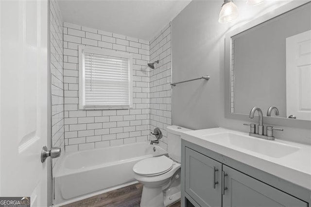 full bathroom with tiled shower / bath, vanity, hardwood / wood-style flooring, and toilet