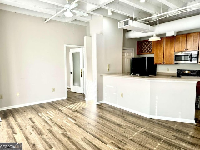 kitchen featuring a high ceiling, black appliances, hanging light fixtures, and wood-type flooring