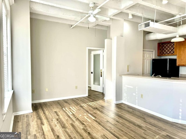 interior space featuring ceiling fan, beam ceiling, hardwood / wood-style floors, and black refrigerator