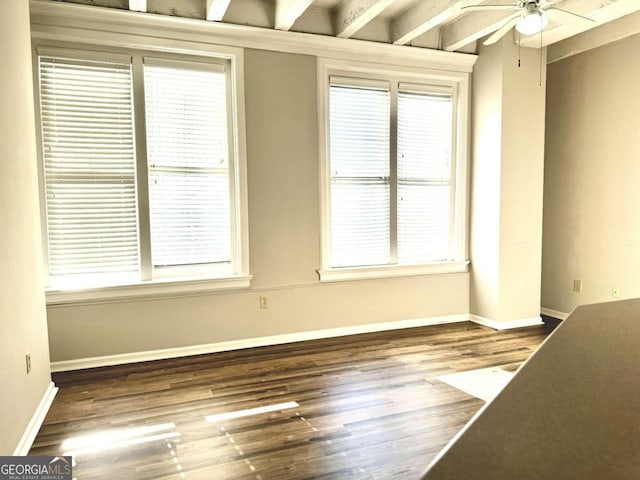 empty room featuring beam ceiling, dark wood-type flooring, and ceiling fan