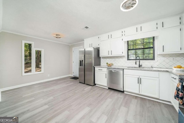 kitchen with stainless steel appliances, crown molding, sink, white cabinetry, and light hardwood / wood-style floors