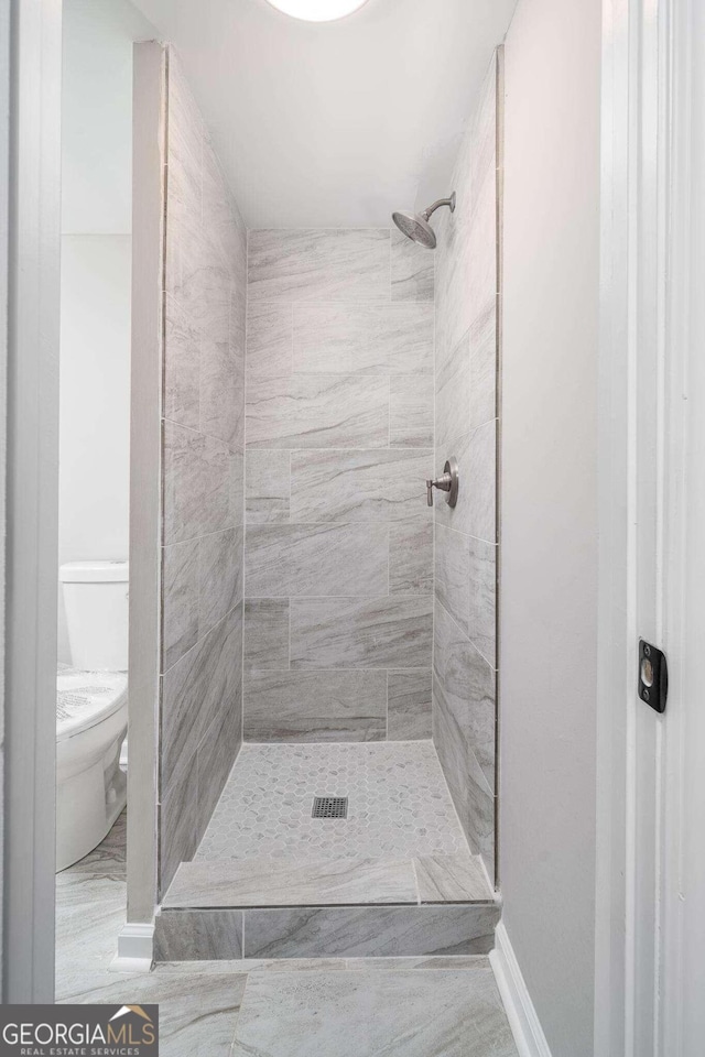 bathroom featuring tiled shower and toilet