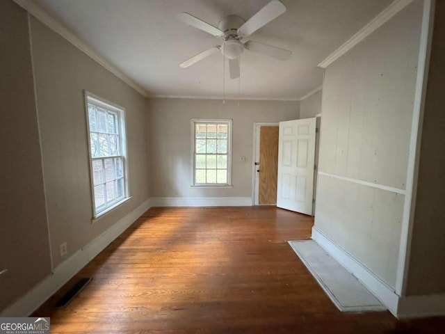 empty room featuring crown molding, dark wood-type flooring, and ceiling fan