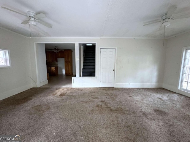 unfurnished room with ceiling fan, a healthy amount of sunlight, and dark colored carpet