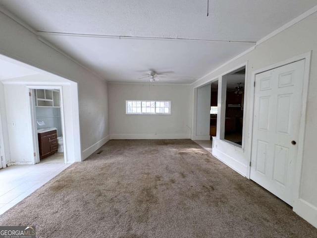 unfurnished living room with crown molding, carpet flooring, and ceiling fan