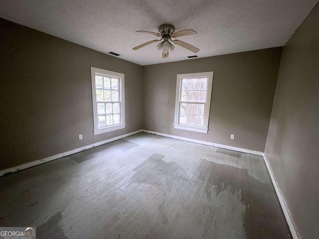 unfurnished room featuring a wealth of natural light, hardwood / wood-style floors, and a textured ceiling