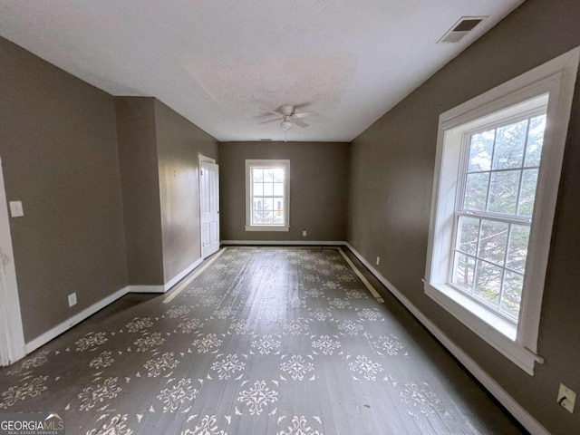 unfurnished room with ceiling fan and a textured ceiling