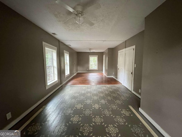 unfurnished room with ceiling fan, a textured ceiling, and dark hardwood / wood-style flooring