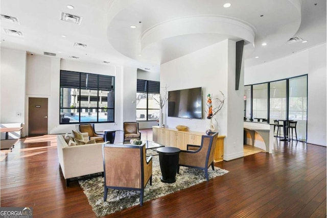 living room with a towering ceiling and dark hardwood / wood-style flooring