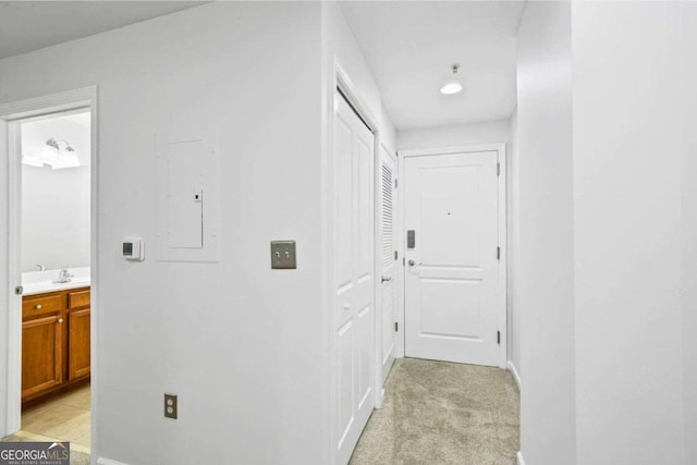 hall with sink, electric panel, and light colored carpet