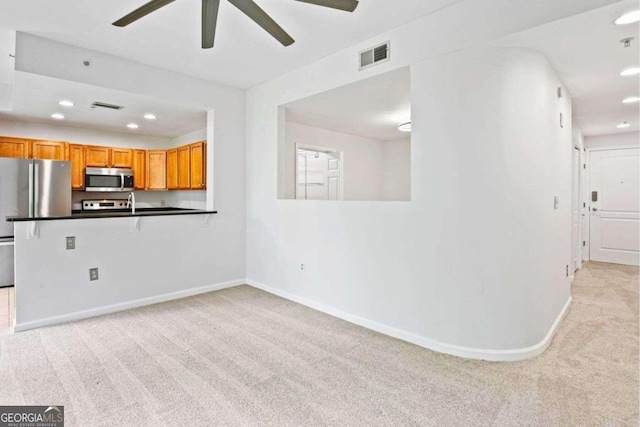 unfurnished living room with light colored carpet and ceiling fan