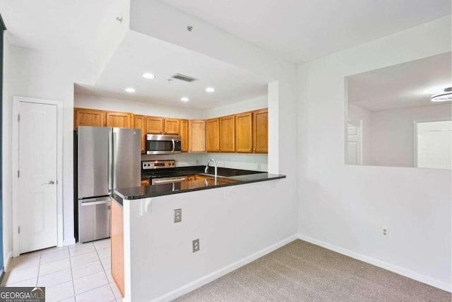 kitchen with appliances with stainless steel finishes, sink, kitchen peninsula, and light colored carpet