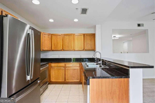 kitchen with kitchen peninsula, light tile patterned floors, dark stone countertops, sink, and stainless steel appliances