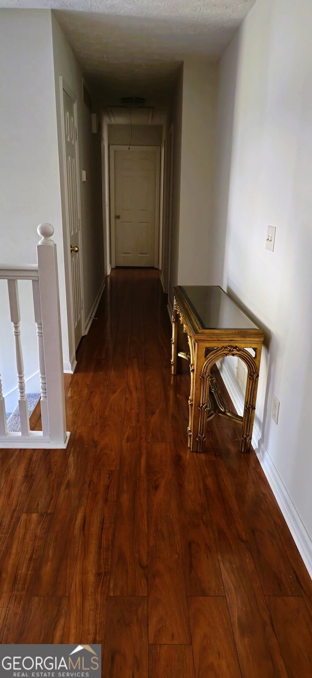 hallway featuring a textured ceiling and dark hardwood / wood-style floors