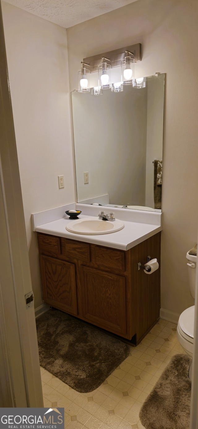 bathroom with vanity, toilet, a textured ceiling, and tile patterned flooring