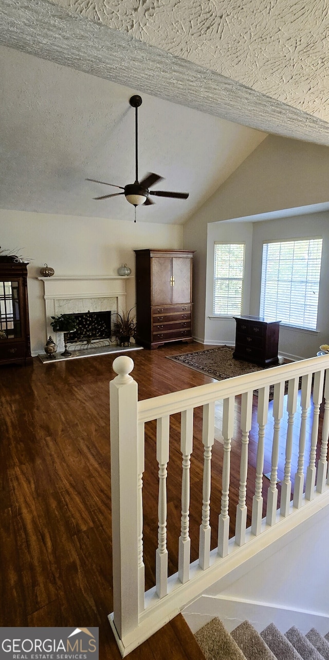 stairway with lofted ceiling, ceiling fan, a premium fireplace, a textured ceiling, and hardwood / wood-style flooring