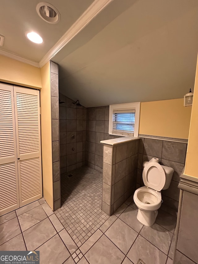 bathroom with ornamental molding, a tile shower, toilet, and tile patterned floors