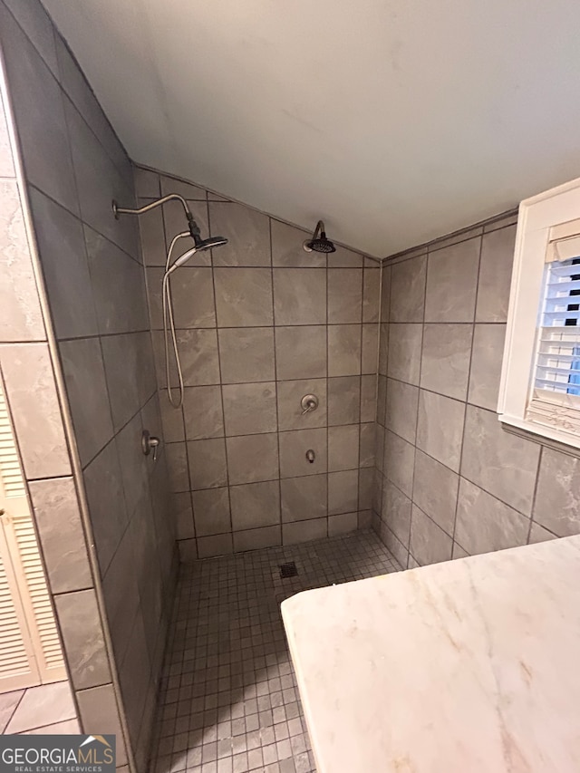 bathroom with a tile shower, tile patterned floors, and lofted ceiling