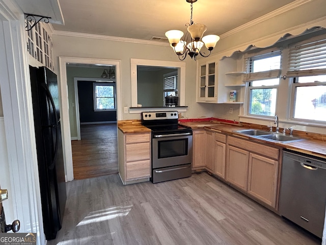 kitchen with sink, wood counters, light hardwood / wood-style floors, stainless steel appliances, and pendant lighting