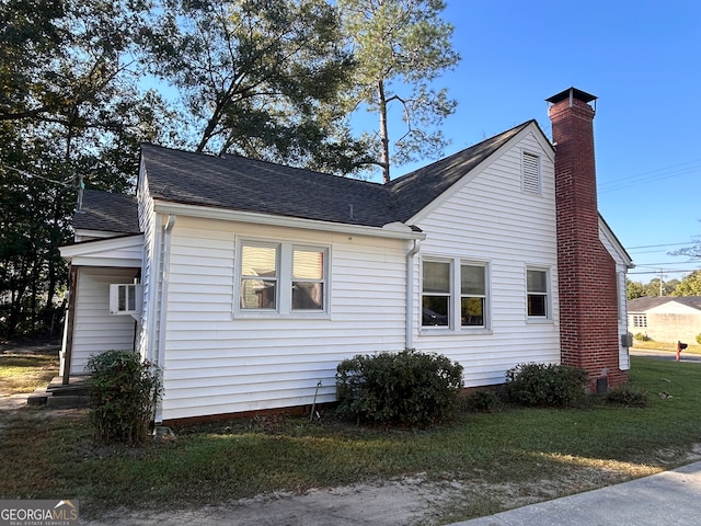 view of side of property with a lawn and a wall mounted air conditioner