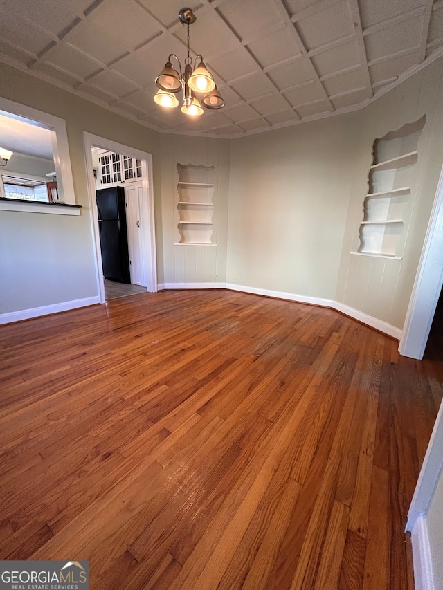 interior space featuring built in features, wood-type flooring, and a chandelier