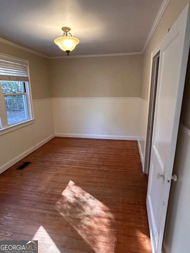 empty room with ornamental molding and dark hardwood / wood-style floors