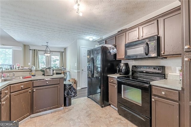 kitchen featuring hanging light fixtures, sink, black appliances, dark brown cabinetry, and a textured ceiling