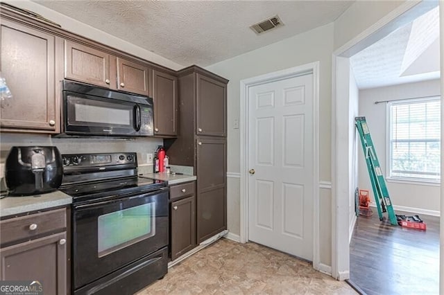 kitchen featuring light hardwood / wood-style floors, a textured ceiling, black appliances, and dark brown cabinetry