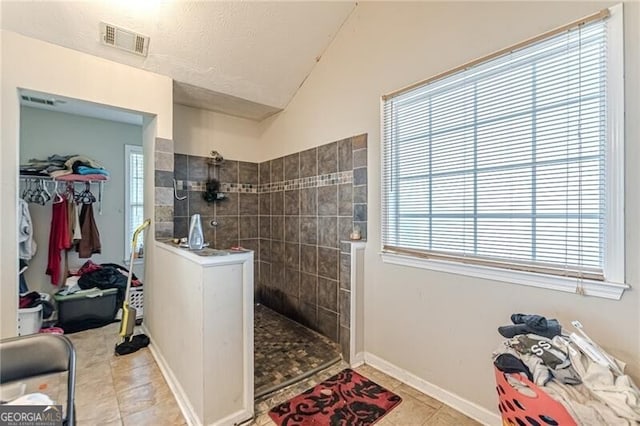 bathroom with a tile shower, tile patterned floors, and plenty of natural light