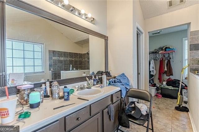 bathroom featuring vanity, lofted ceiling, and tile patterned flooring