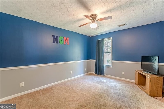 empty room with a textured ceiling, light colored carpet, and ceiling fan