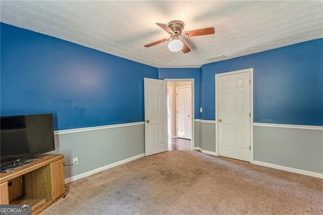 interior space with a textured ceiling, carpet floors, and ceiling fan