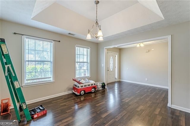 interior space featuring a tray ceiling, a chandelier, and dark hardwood / wood-style floors