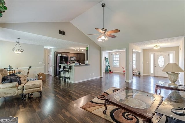 living room featuring dark wood-type flooring, high vaulted ceiling, and ceiling fan with notable chandelier