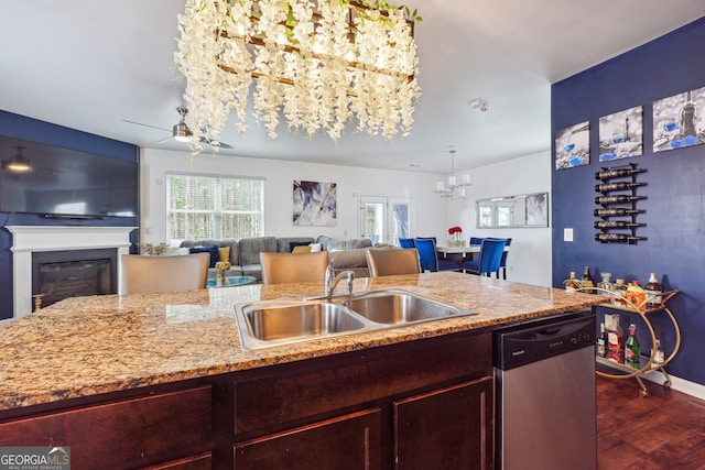 kitchen featuring sink, ceiling fan with notable chandelier, stainless steel dishwasher, light stone counters, and dark hardwood / wood-style floors