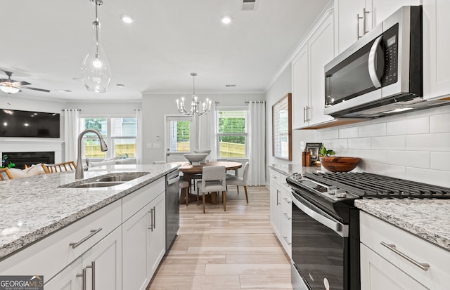 kitchen with tasteful backsplash, sink, hanging light fixtures, stainless steel appliances, and white cabinets