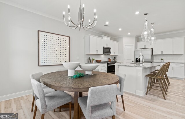 dining room featuring ornamental molding, sink, and light hardwood / wood-style floors