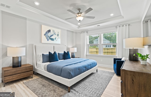 bedroom with ornamental molding, ceiling fan, light hardwood / wood-style floors, and a raised ceiling