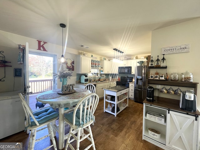 kitchen with dark wood-type flooring, hanging light fixtures, sink, black appliances, and white cabinets