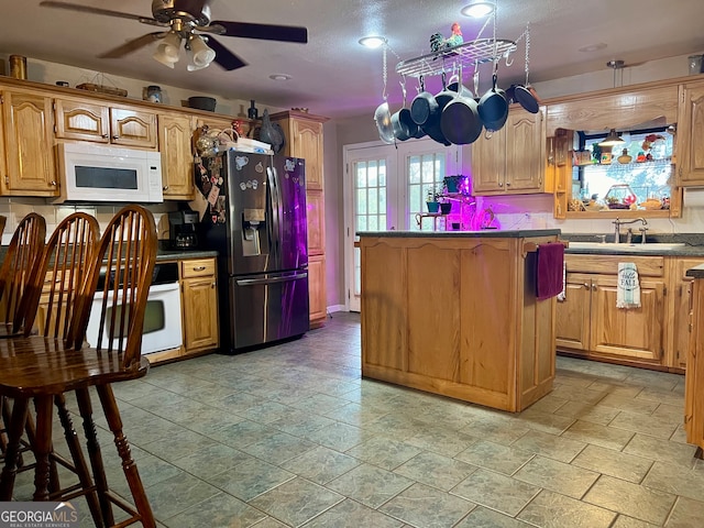 kitchen featuring a textured ceiling, sink, white appliances, and ceiling fan