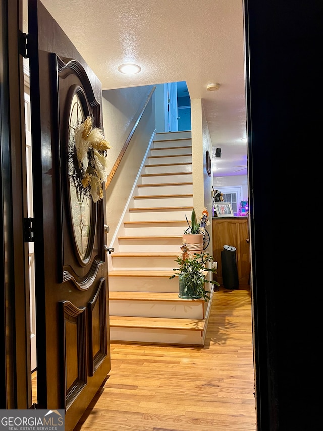 stairs featuring wood-type flooring and a textured ceiling