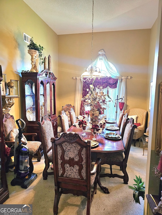 carpeted dining area featuring a textured ceiling and a chandelier