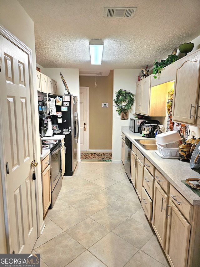 kitchen featuring appliances with stainless steel finishes, sink, a textured ceiling, light tile patterned floors, and light brown cabinets