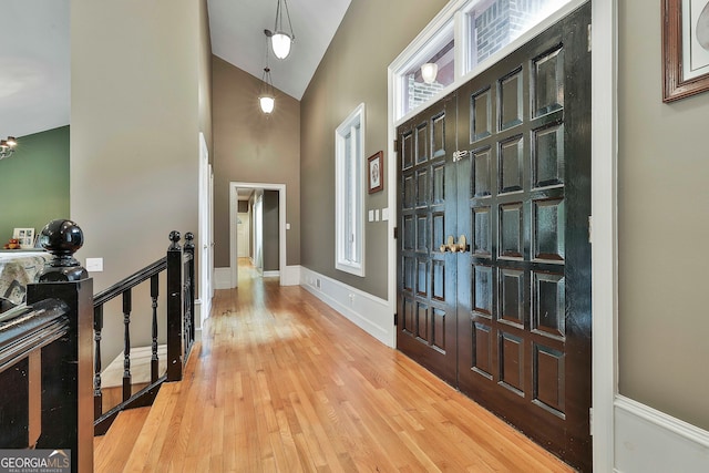 foyer with plenty of natural light, light wood-type flooring, and high vaulted ceiling