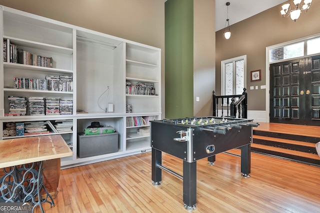 recreation room with hardwood / wood-style flooring and a towering ceiling