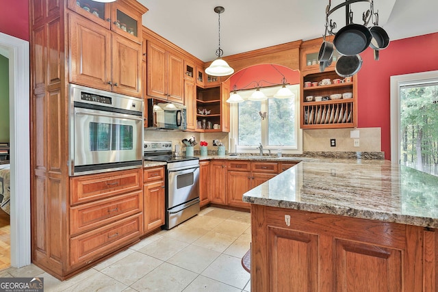 kitchen with a wealth of natural light, stainless steel appliances, hanging light fixtures, and light stone countertops