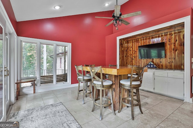 tiled dining area featuring high vaulted ceiling, bar area, and ceiling fan