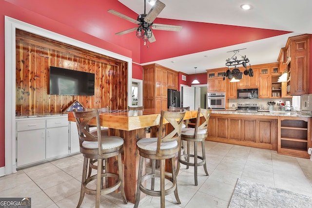 kitchen featuring kitchen peninsula, hanging light fixtures, black appliances, ceiling fan, and light tile patterned flooring